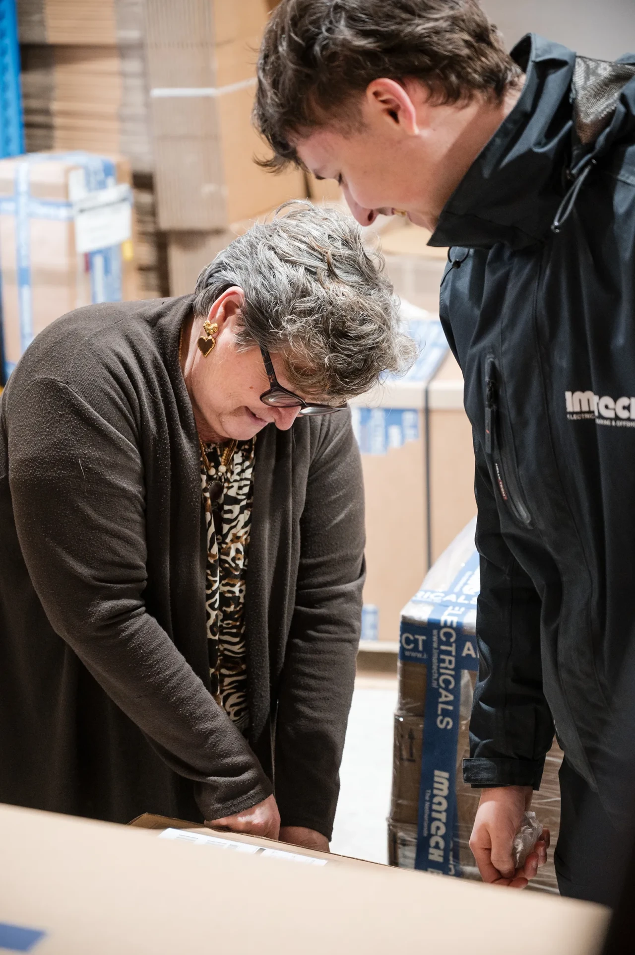 Two Imatech employees review shipment details together in the warehouse, checking a package before dispatch.