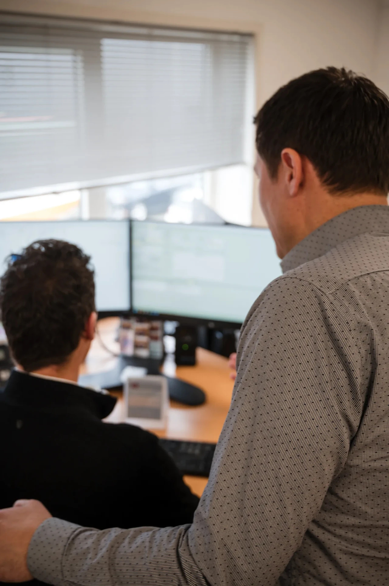 Two Imatech employees review technical information together at a dual-monitor workstation, discussing requirements and preparing a detailed quotation.